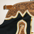 Close-up of a leather saddle with intricate tooled design on a beige background