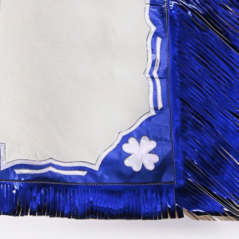 Blue fringe fabric with white floral design on a textured white background