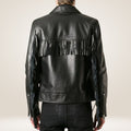 Black leather jacket with fringe details on a plain background