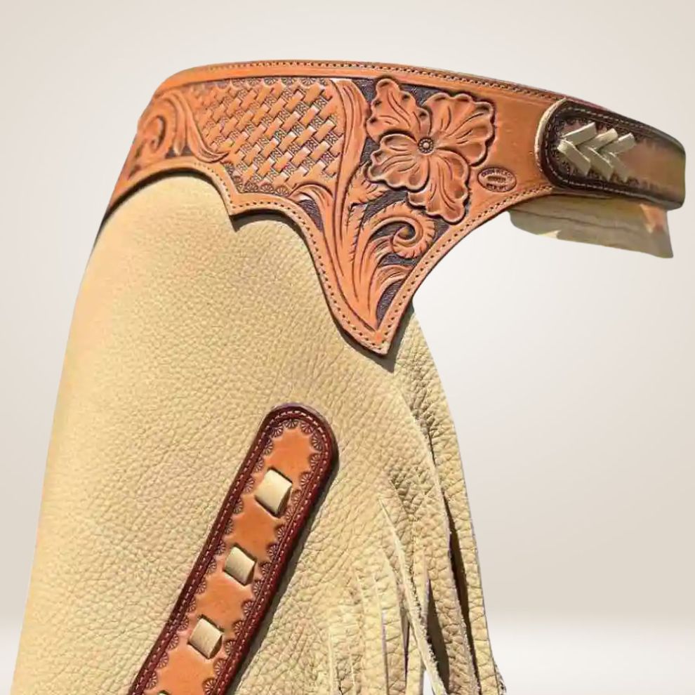 Beige leather chaps with brown leather accents and fringes on a light beige background