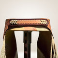 Close-up of a saddle with intricate leatherwork on a plain background