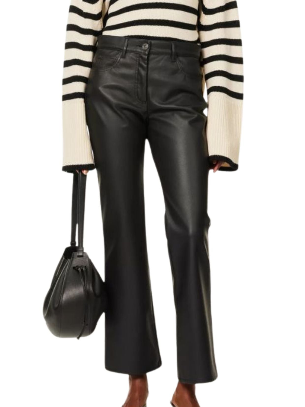 Person wearing a black and white striped sweater and black leather pants, holding a black handbag.